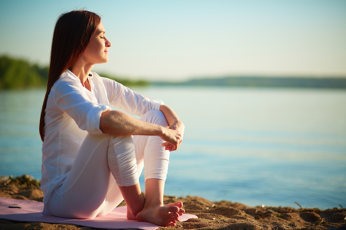side,view,of,serene,woman,sitting,on,sandy,beach,against